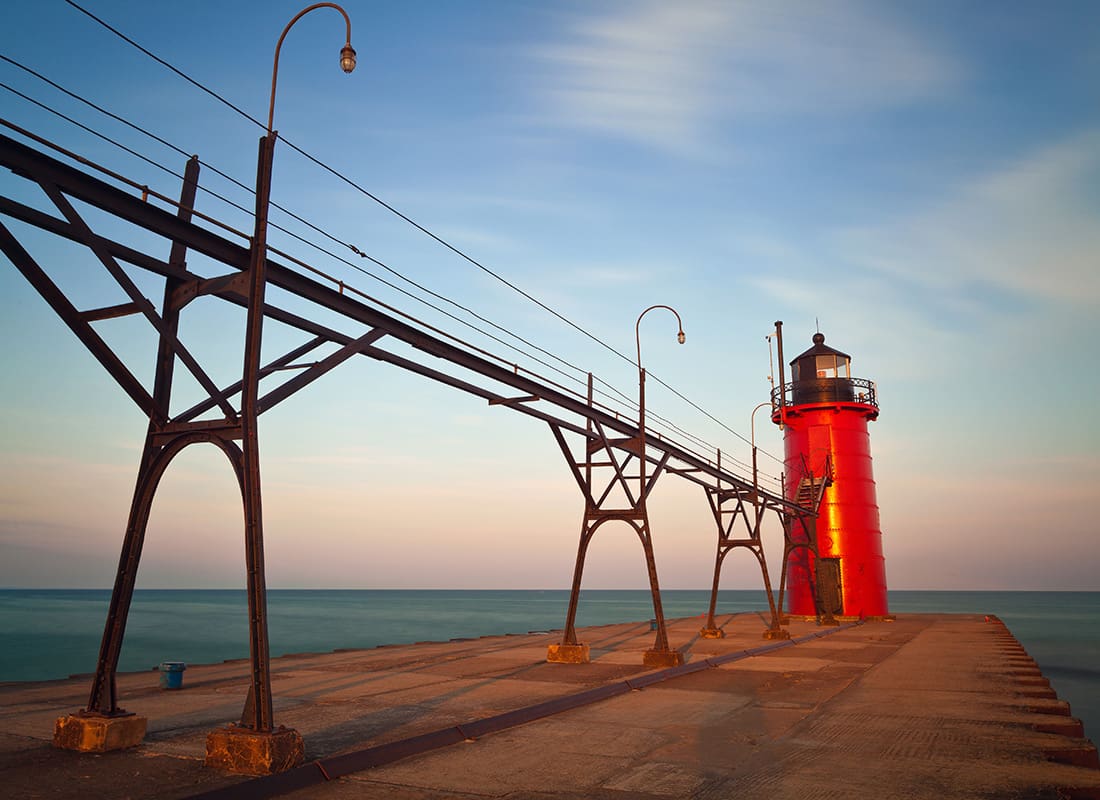 Contact - View of a Red Lighthouse by the Water Against a Colorful Sunset Sky in South Haven Michigan